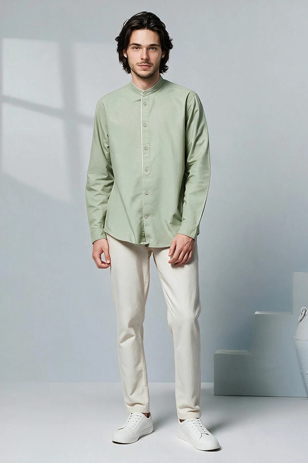 Tenue baju koko indonésienne : chemise vert clair à col mandarin et pantalon blanc cassé sur un mannequin homme